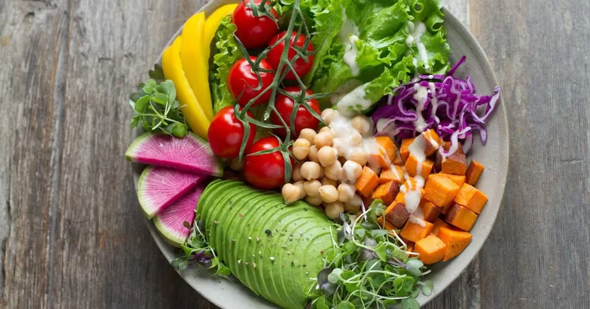 A bowl of salad with avocado, chickpeas, tomatoes and radish on a wooden table