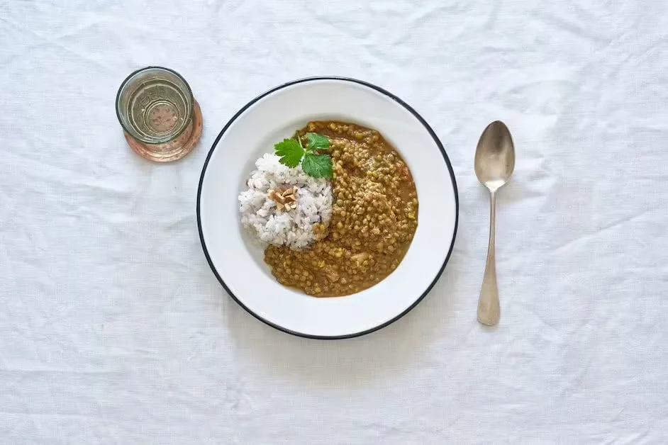 A bowl of lentil porridge with herbs and a spoon on a linen cloth