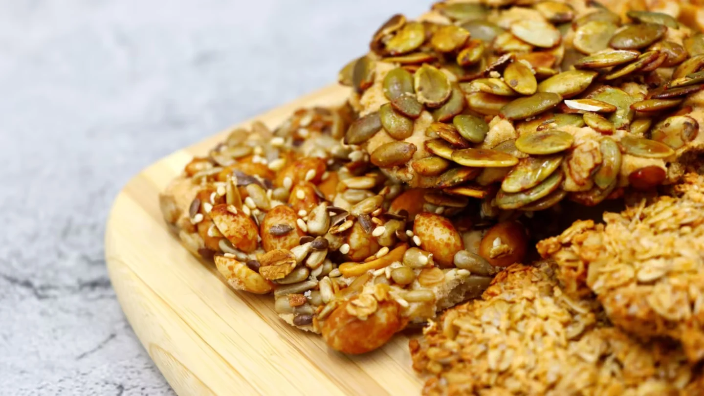 Close-up of various healthy homemade mixed nut and seed snacks on a wooden board.