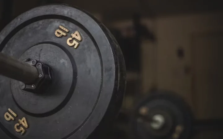 A loaded 45 pound barbell plate in a dim gym