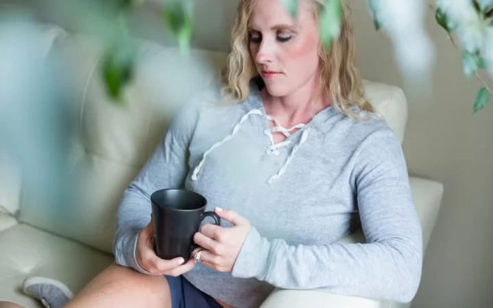 A woman sitting on a sofa holding a mug of tea