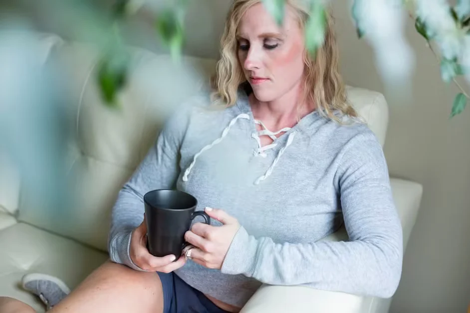 A woman sitting on a sofa holding a mug of tea
