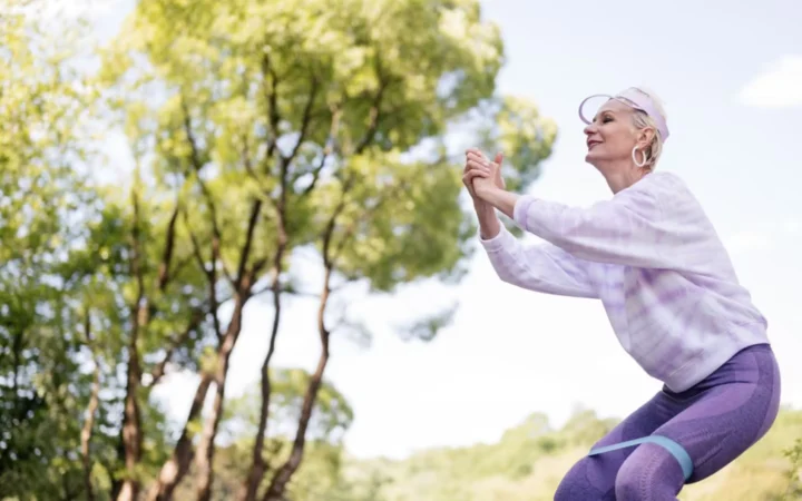 Senior woman exercises in a park with a resistance band, embracing a healthy lifestyle.