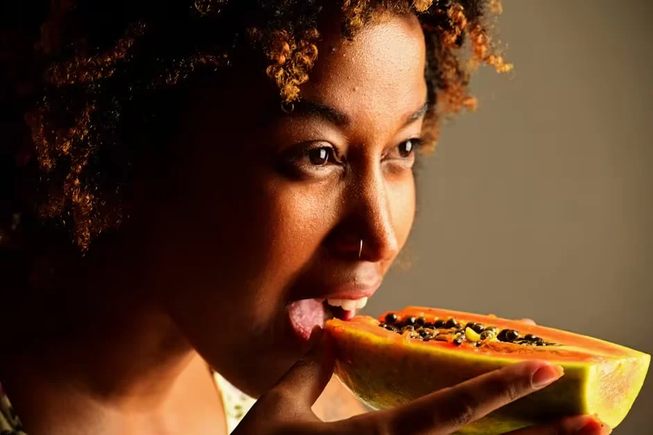A woman eating a slice of fresh papaya