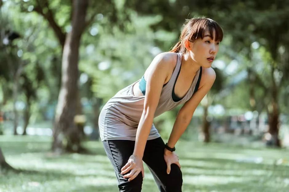 A woman resting her hands on her knees after running outdoors