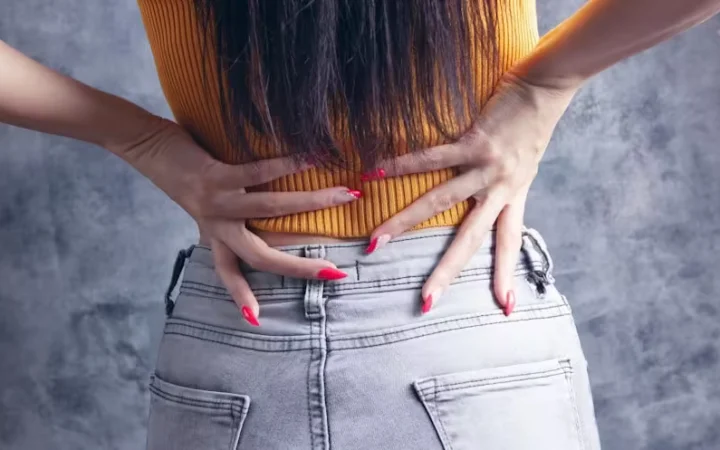 A woman pressing both hands into her lower back
