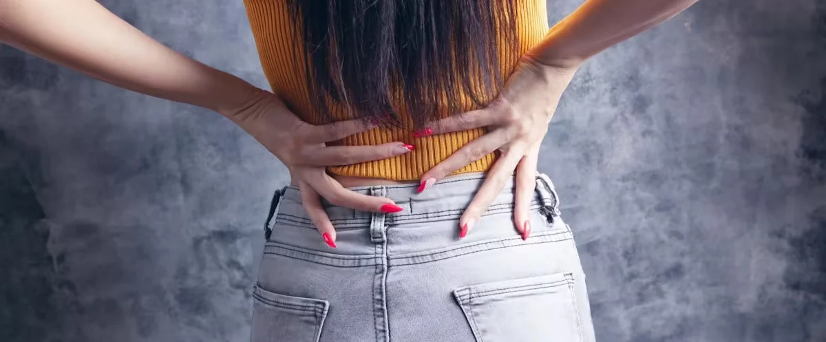 A woman pressing both hands into her lower back