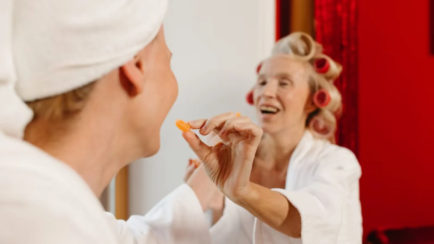 Senior women in bathrobes with hair curlers sharing laughter and luxury spa time indoors.