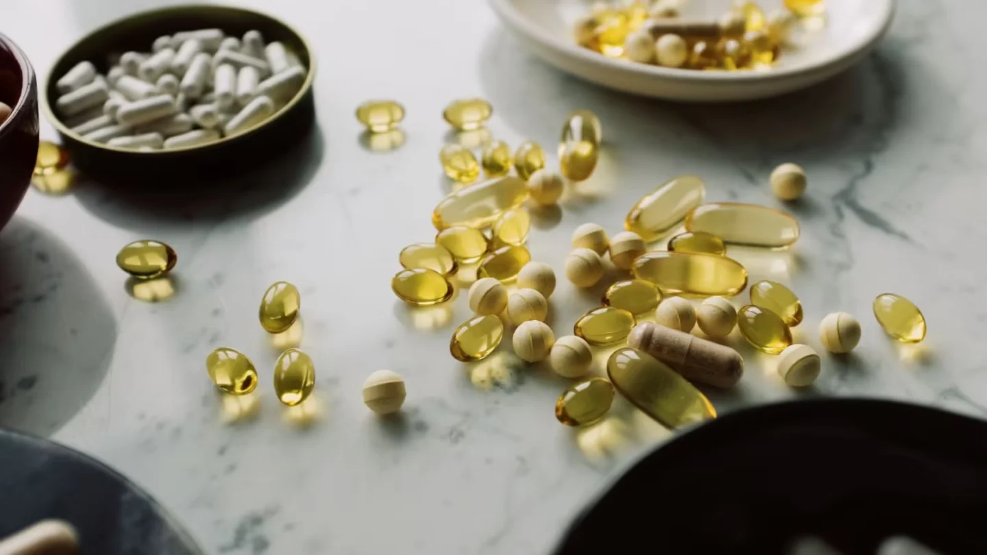 Close-up of assorted pills and supplements arranged on a marble surface, highlighting healthcare and wellness themes.