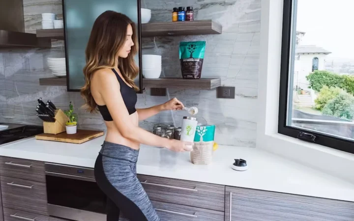 A woman preparing a drink at a kitchen counter