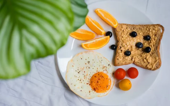 Fried eggs, wholegrain toast with blueberries and orange segments