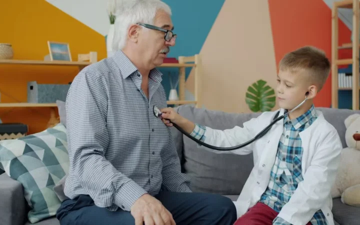 A boy listening to an older man's chest with a stethoscope at home