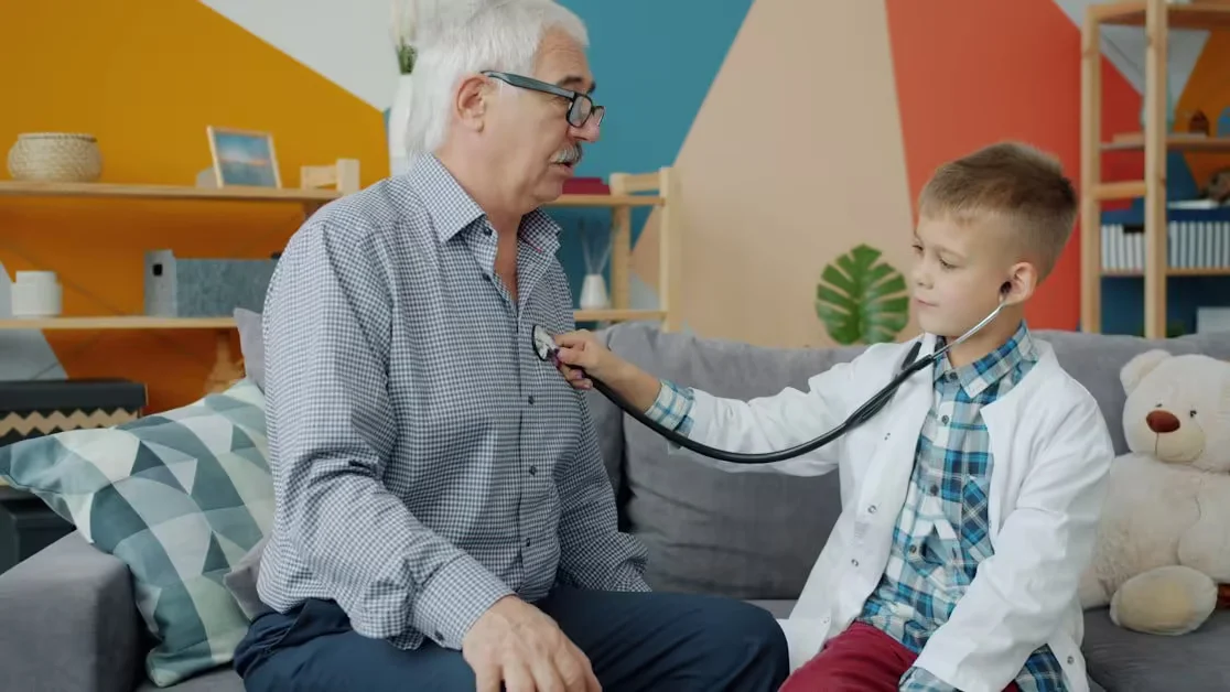 A boy listening to an older man's chest with a stethoscope at home