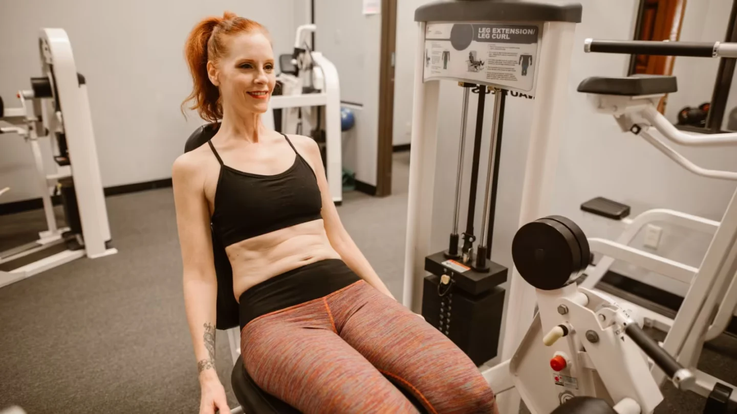 Woman performing leg workout in gym, showcasing fitness and health lifestyle.