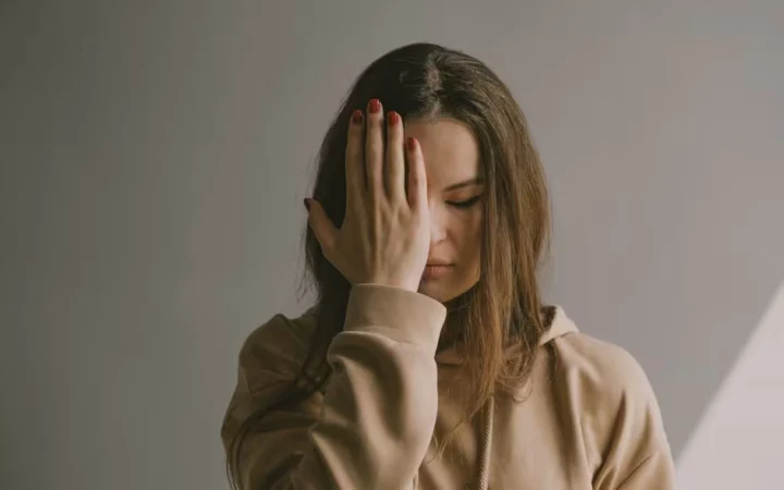 A woman standing with one hand covering her eyes
