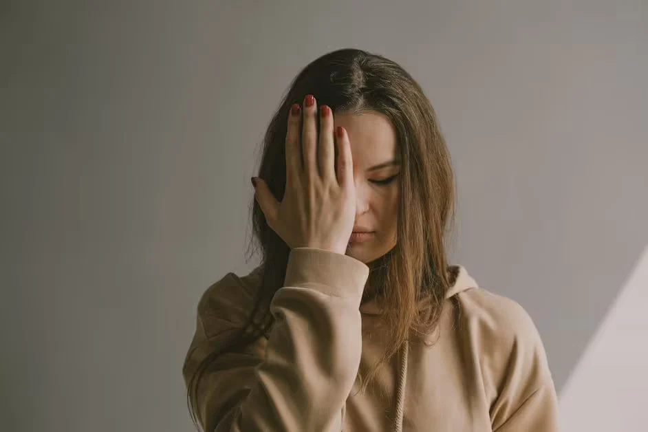 A woman standing with one hand covering her eyes