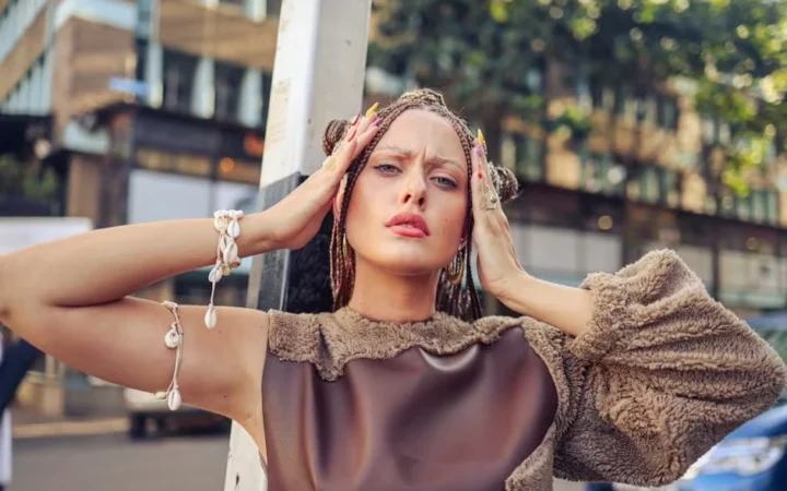 A woman outdoors with both hands pushed into her hair