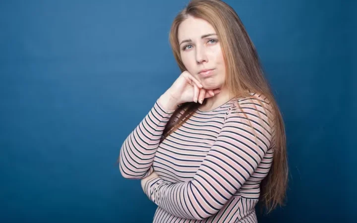 A woman resting her chin on her hand against a blue background