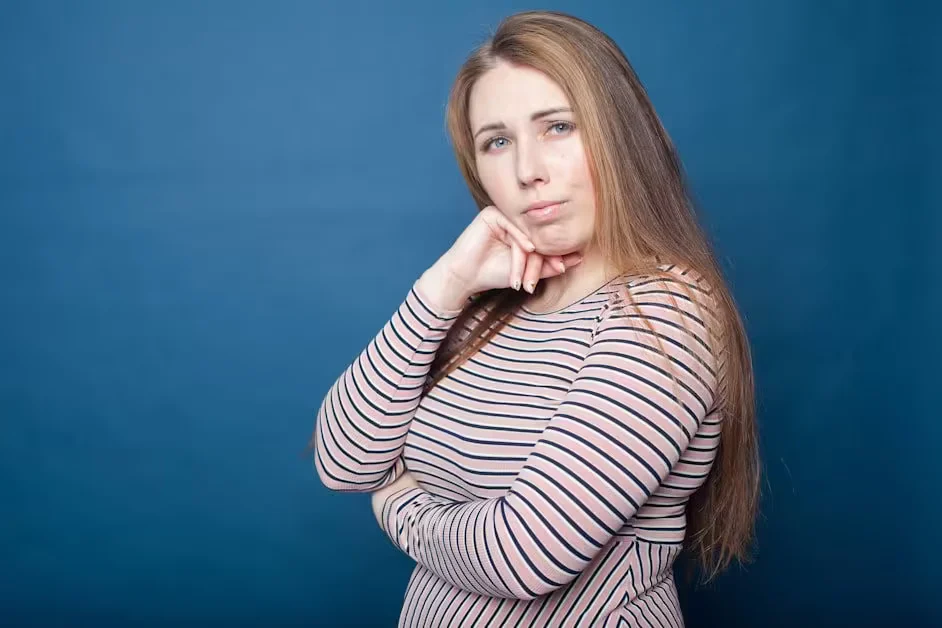 A woman resting her chin on her hand against a blue background