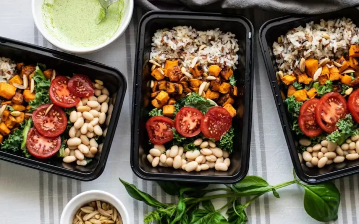 Meal prep containers of rice, roasted vegetables, beans and tomatoes