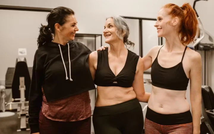 Three women of different ages together in a gym, one grey-haired