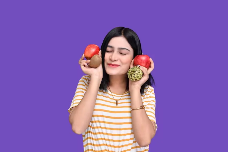 A woman holding pieces of fruit up beside her face
