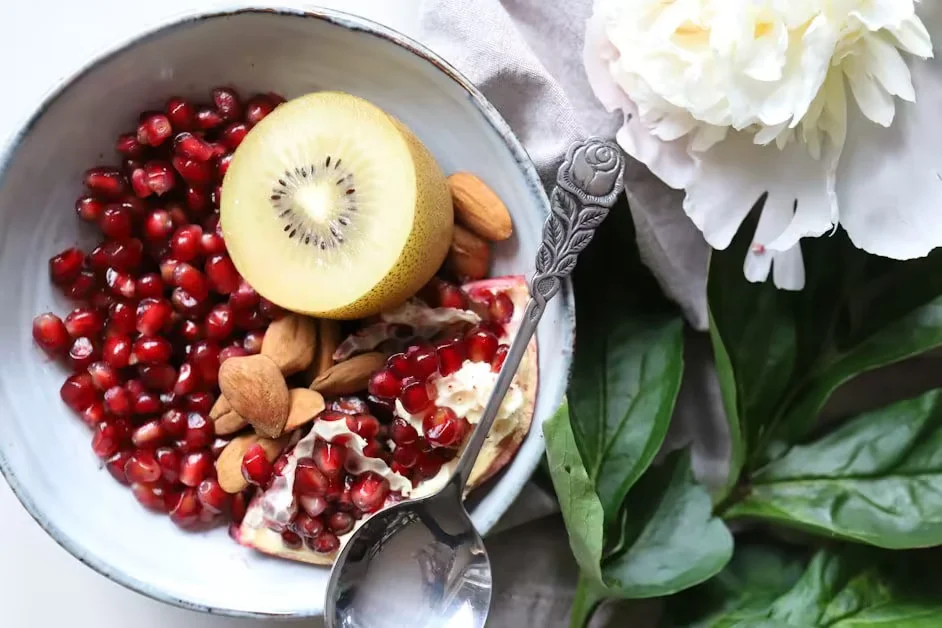 A bowl of pomegranate seeds, kiwi and almonds