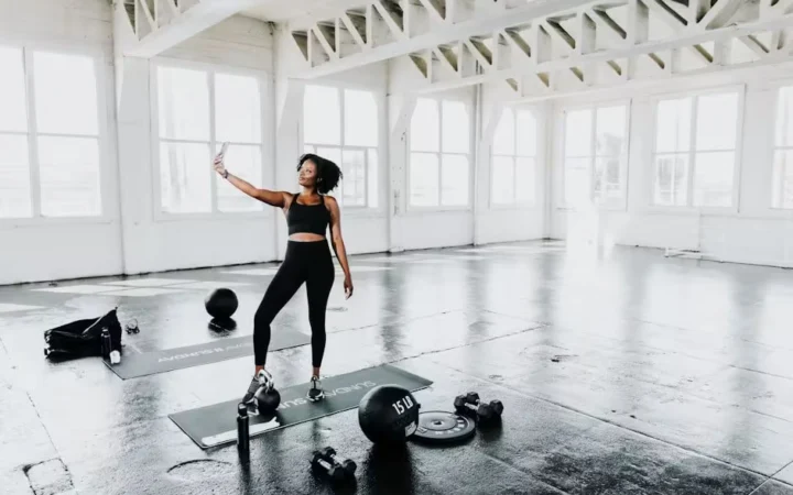 A woman standing over kettlebells in a bright studio