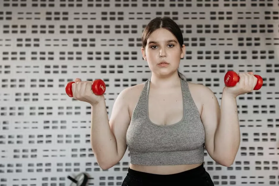A woman raising a pair of light dumbbells
