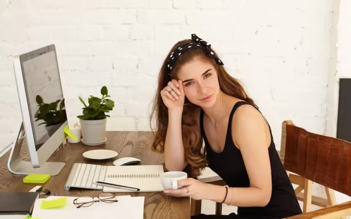 A woman at a desk resting her head on one hand