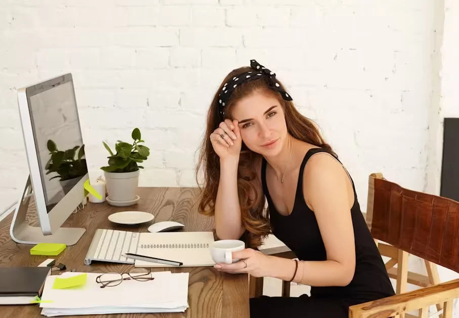 A woman at a desk resting her head on one hand