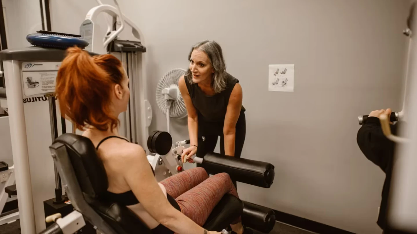 Personal trainer guiding women during a workout session in a gym setting.