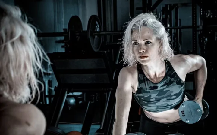 A grey-haired woman lifting a dumbbell in a gym