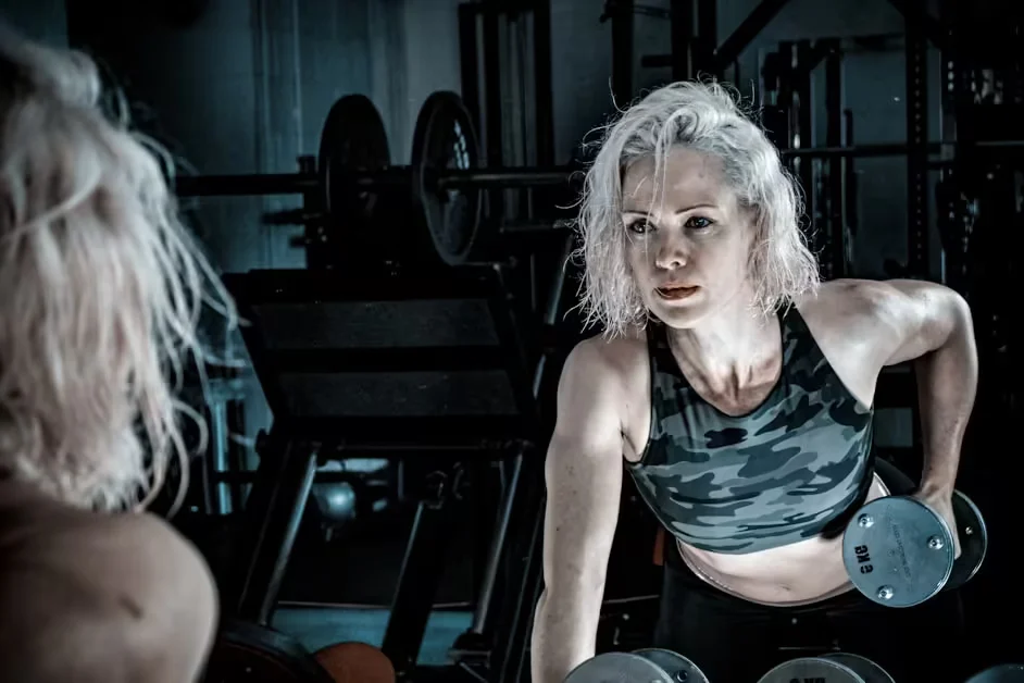 A grey-haired woman lifting a dumbbell in a gym