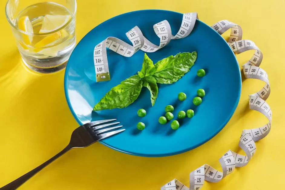 A blue plate of peas and basil beside a tape measure
