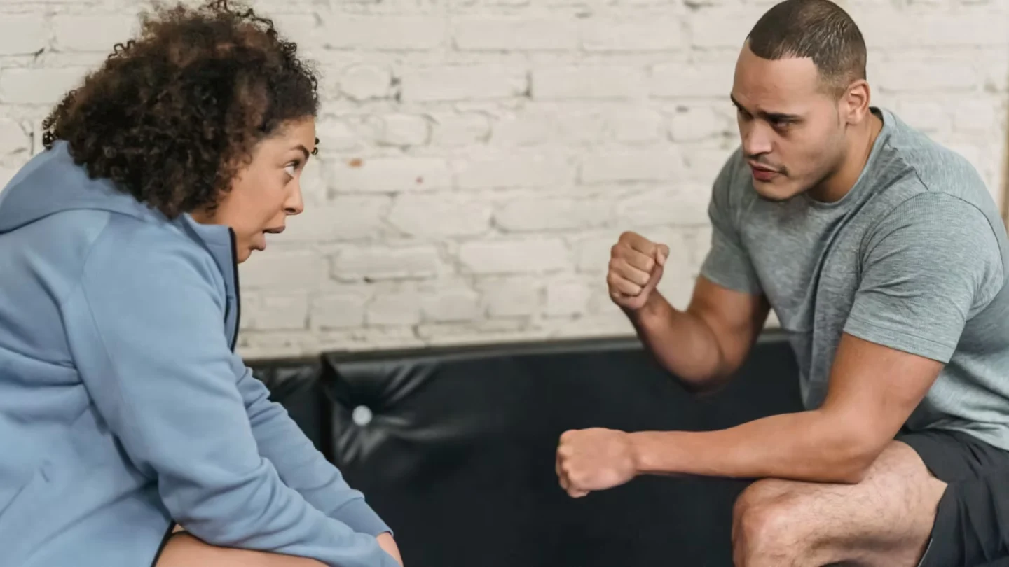 Side view of sportive black personal trainer showing technique of exercise to African American woman while looking at each