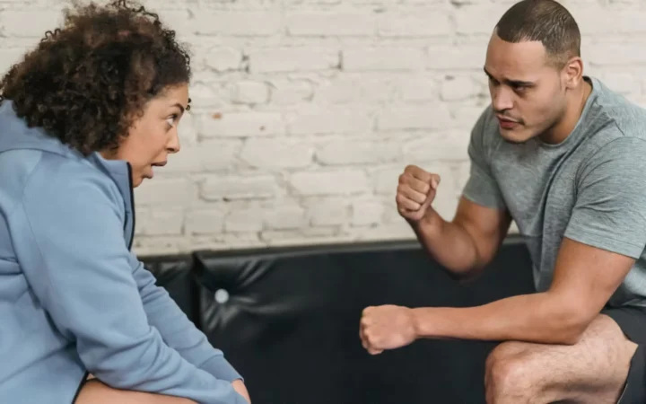 Side view of sportive black personal trainer showing technique of exercise to African American woman while looking at each