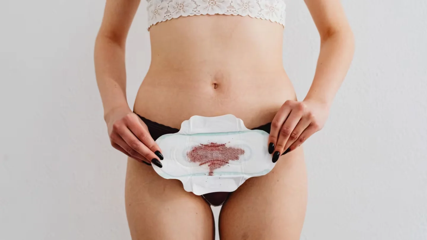 Woman holds a menstrual pad demonstrating feminine hygiene in an indoor setting.