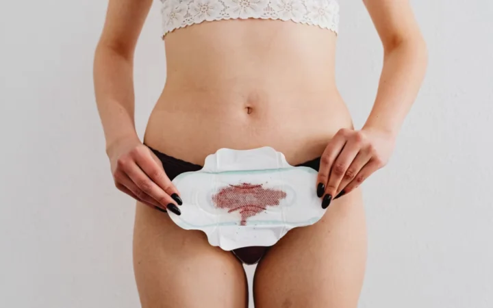 Woman holds a menstrual pad demonstrating feminine hygiene in an indoor setting.