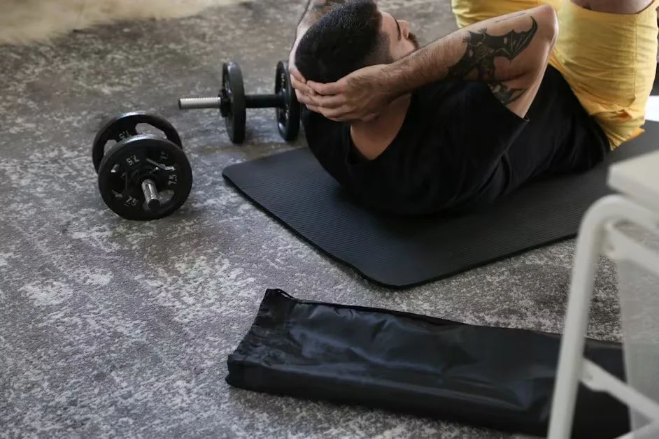 A person lying back on a mat beside dumbbells