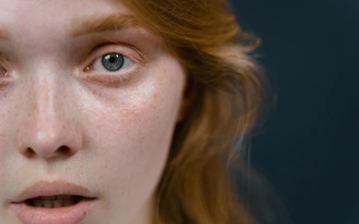 Close-up of a woman's face showing an emotional expression, highlighting her eye and skin texture.