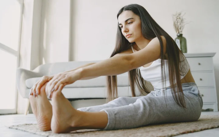 Young woman stretches on a rug in a light-filled room, embracing home fitness.